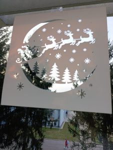 Postavljanje božićne šablone na prozor prije nanošenja umjetnog snijega.