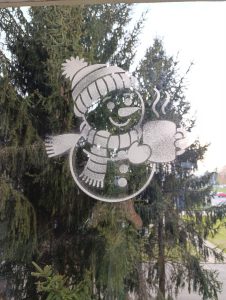 snješko s kapom i šalicom na prozoru, izrađen božićnom šablonom i umjetnim snijegom